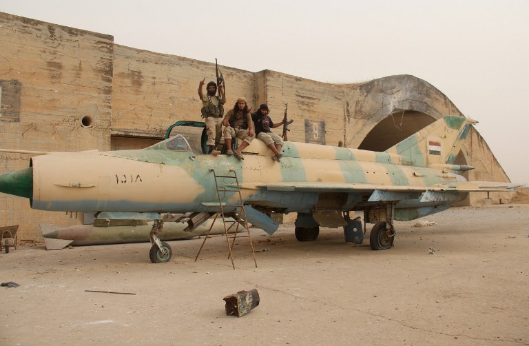 Members of Al-Qaeda's Syrian affiliate and its allies sit on top of a former Syrian army figther jet after they seized the Abu Duhur military airport, the last regime-held military base in northwestern Idlib province on September 9, 2015 in the latest setback for President Bashar al-Assad's forces. Al-Nusra Front and a coalition of mostly Islamist groups captured the military airport after a siege that lasted two years, the Syrian Observatory for Human Rights monitor said. AFP PHOTO / OMAR HAJ KADOUR